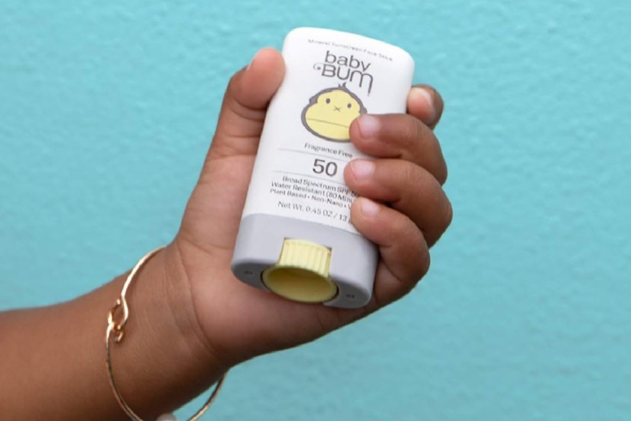 baby hand holding sunscreen stick