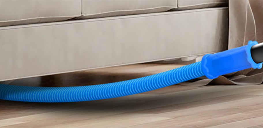 person using lint cleaner to clean under a sofa