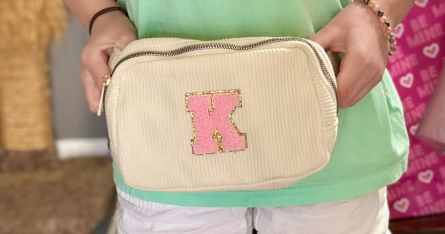 cream color belt bag with initial k on it