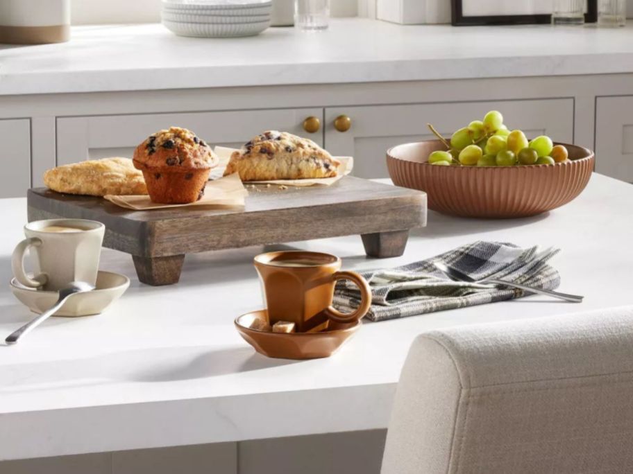 heath and hand serving trivet with scones and muffin on it