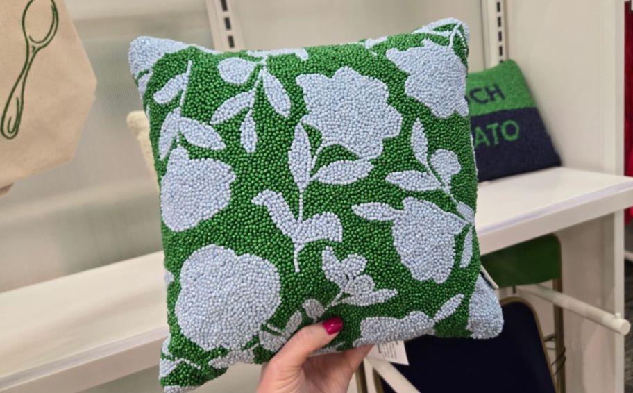 womans hand holding a square beaded floral print pillow