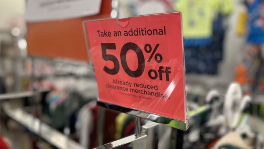 a red sign on top of a clothing rack in a Kohl's store - the sign says Take an additional 50% off clearance