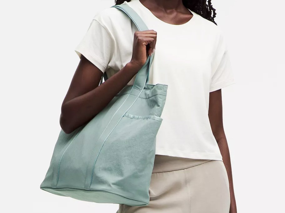 woman in a white tee with a teal tote bag on her shoulder