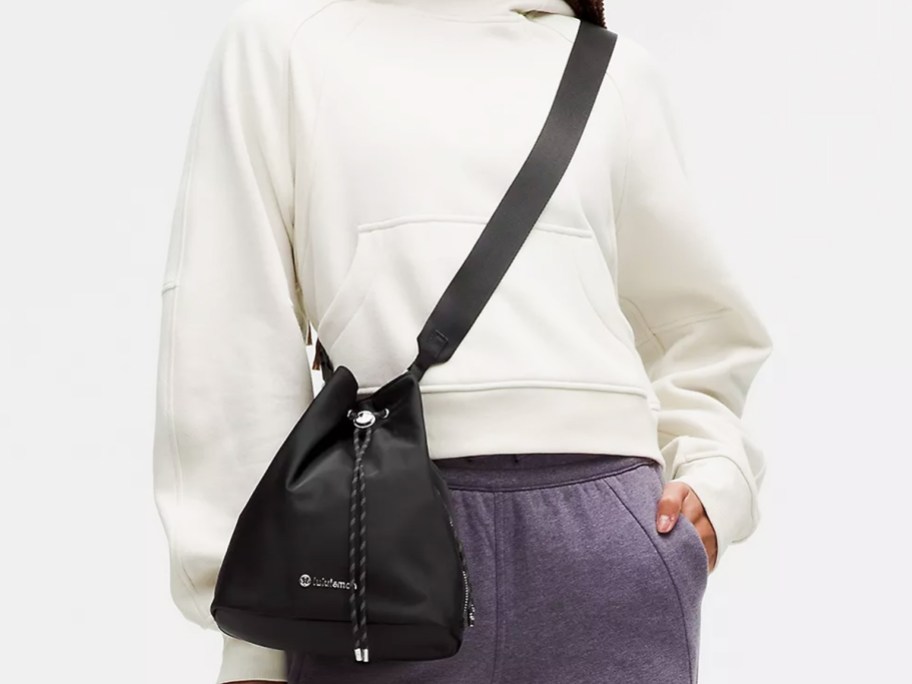 woman in a white hoodie with a black crossbody bucket bag
