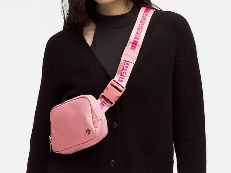 woman in a black sweater with a pink belt bag across chest
