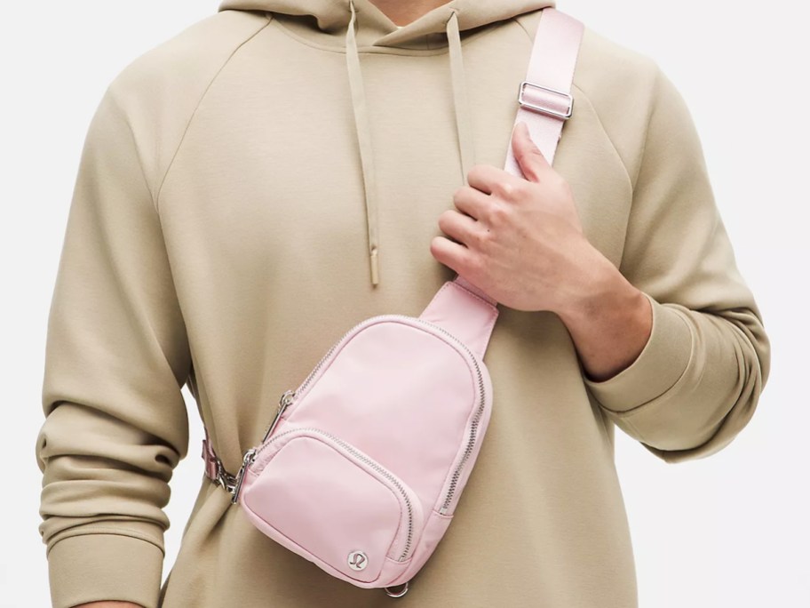 man in a tan hoodie with a pink sling bag across chest