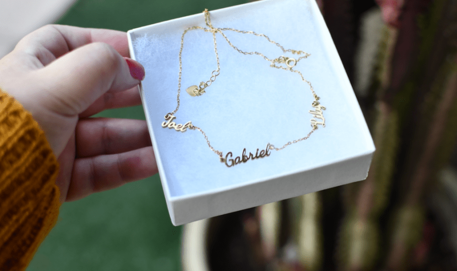hand holding a box with a name necklace inside