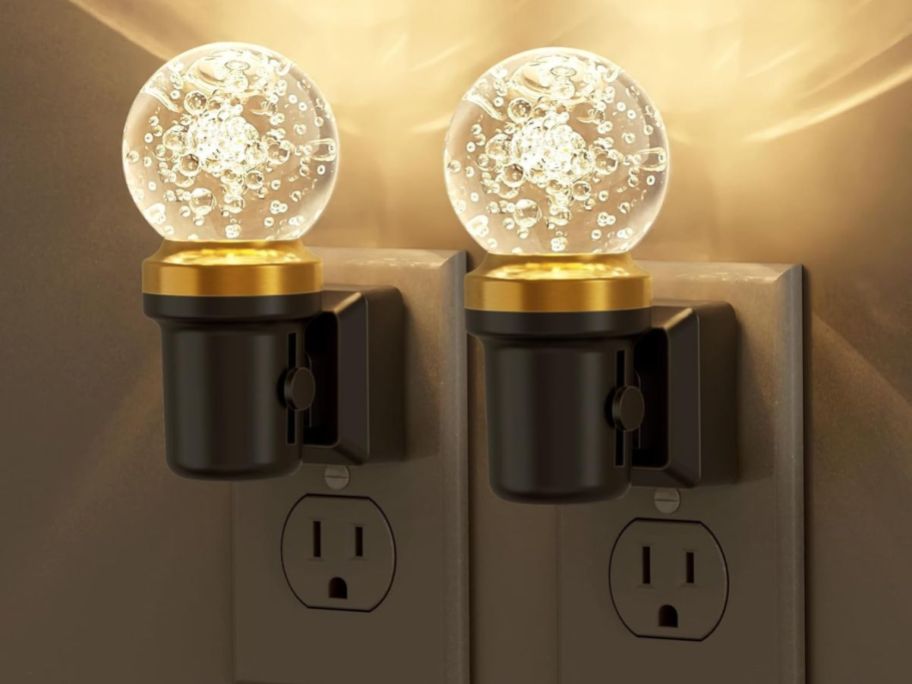 two ball shaped clear night lights in outlet on wall
