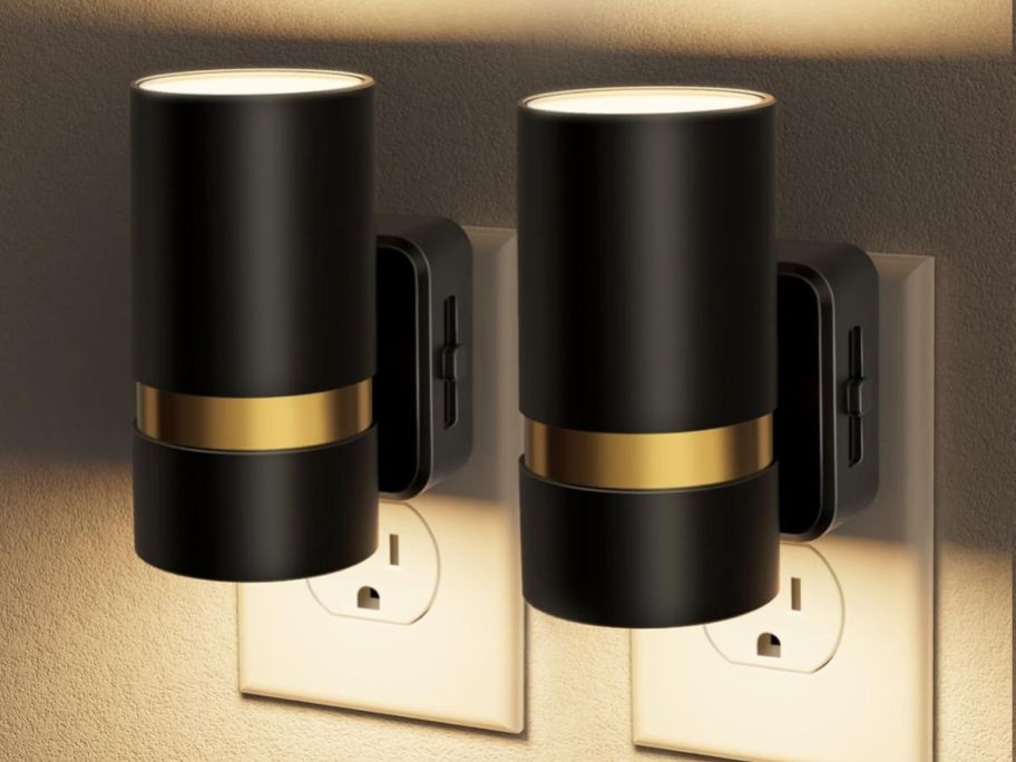 two black and gold night lights in outlet on wall