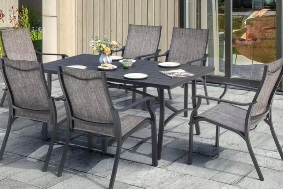 black and gray patio set outdoors with plates and flowers on top 