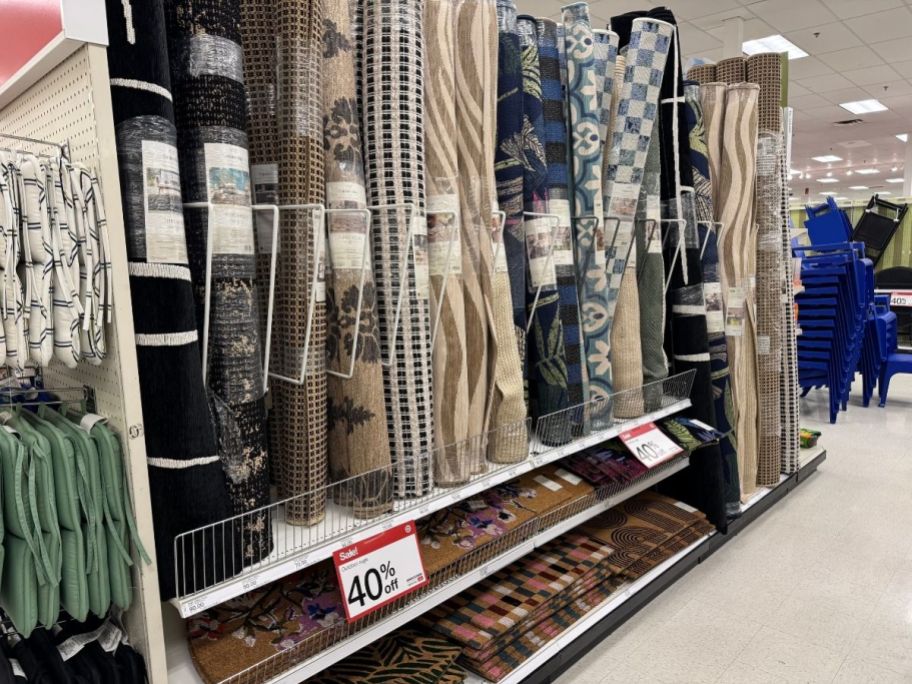a selection of outdoor rugs rolled and stored on a store aisle