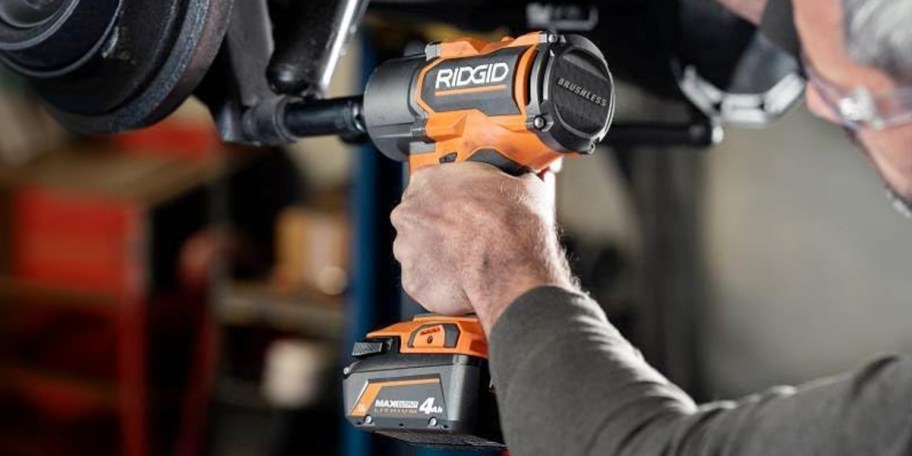 hand using impact wrench on car
