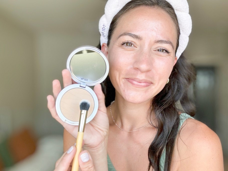 woman holding tarte foundation and brush