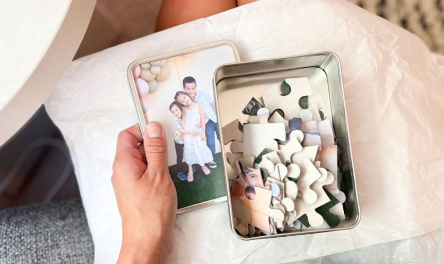 hand holding photo tin with puzzle pieces in box