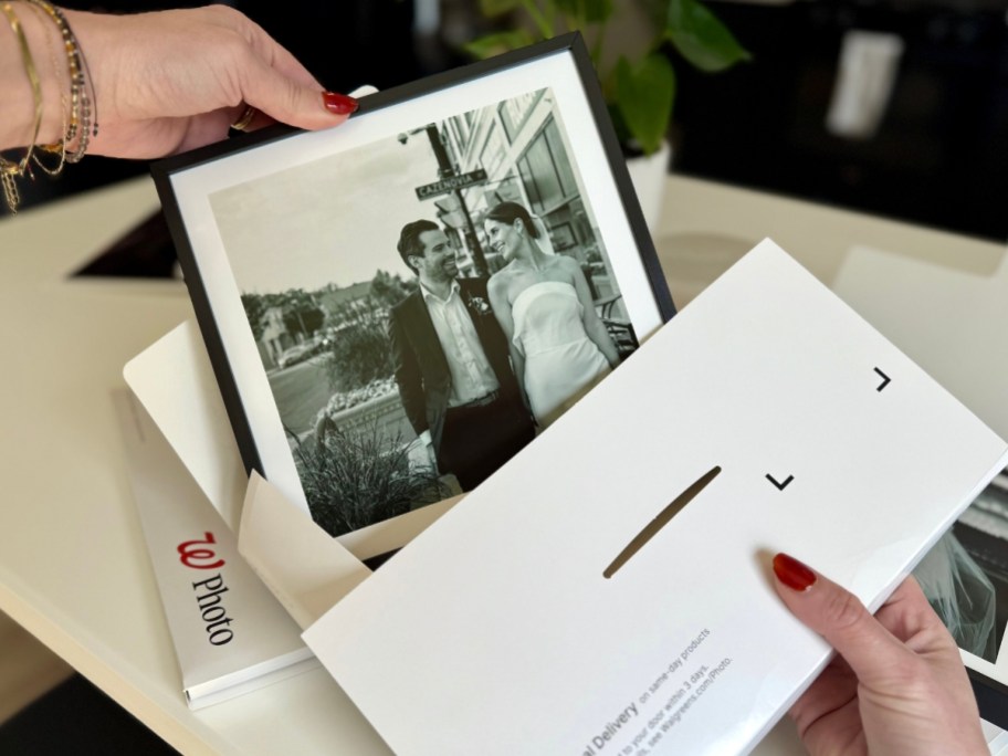 hand pulling a black and white wedding photo in a black Tilepix frame out of an envelope