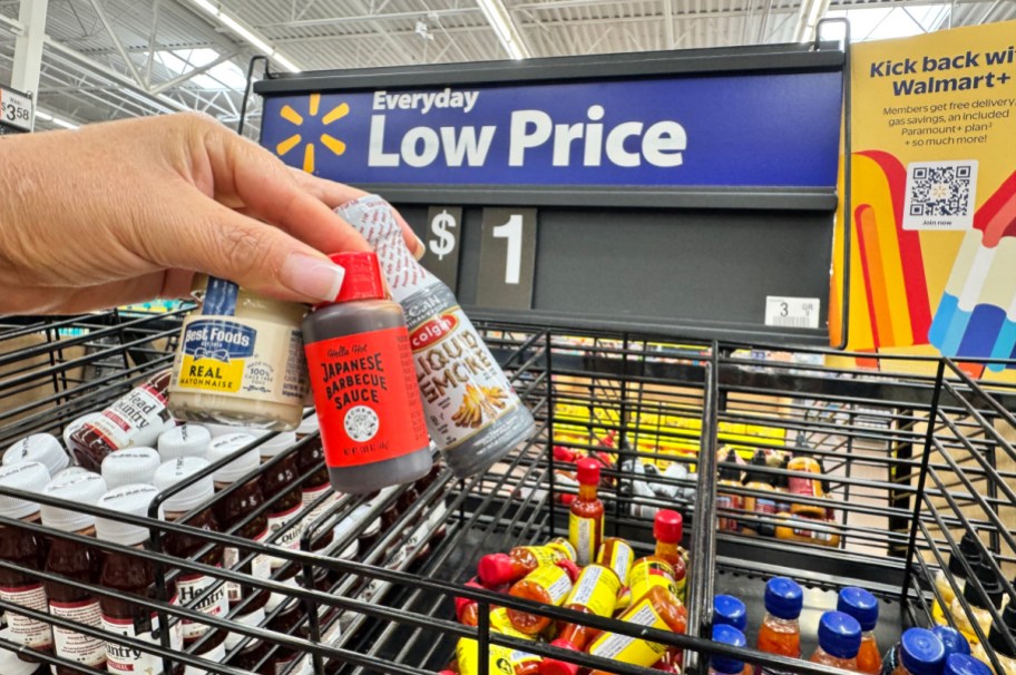 hand holding mini bottles and jars of sauce and mayo in front of a $1 walmart store sign