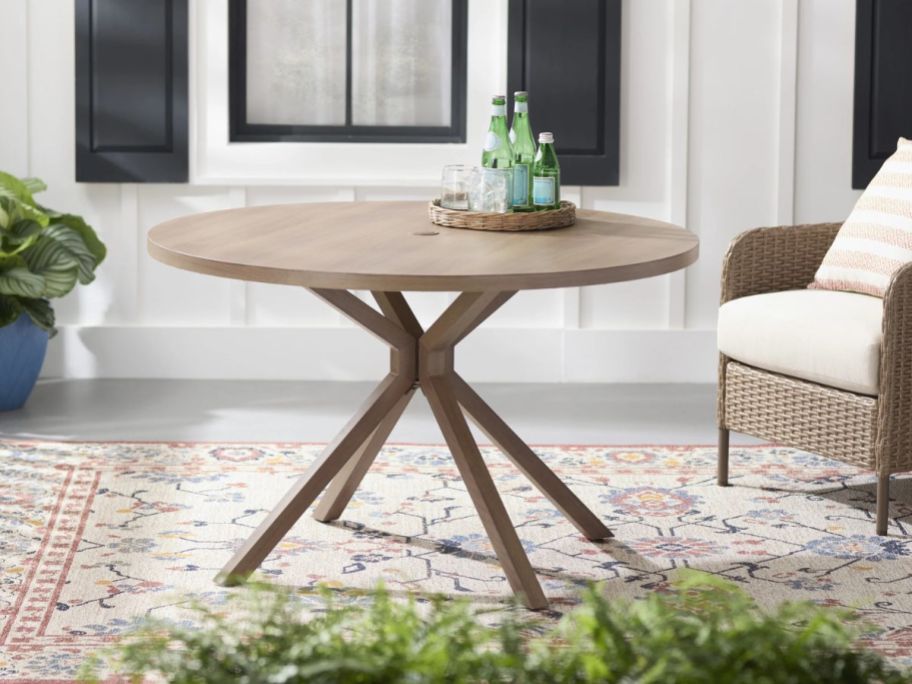 The Mainstays Chelsea Outdoor Dining Table on a patio next to a chair