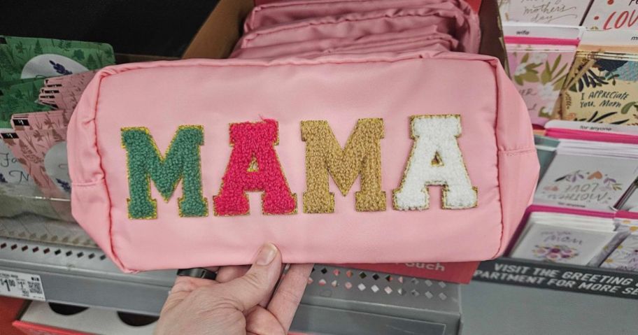 pink Way To Celebrate Mama Pouch with green, pink, gold, and white lettering on it in hand in store