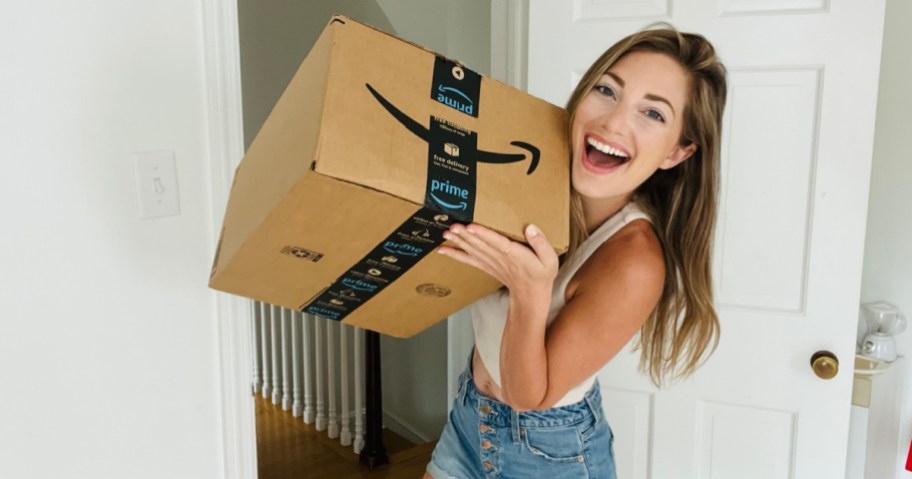 happy woman holding up big amazon shipping box