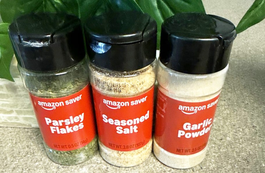 three bottles of Amazon Saver spices on counter in front of green plant
