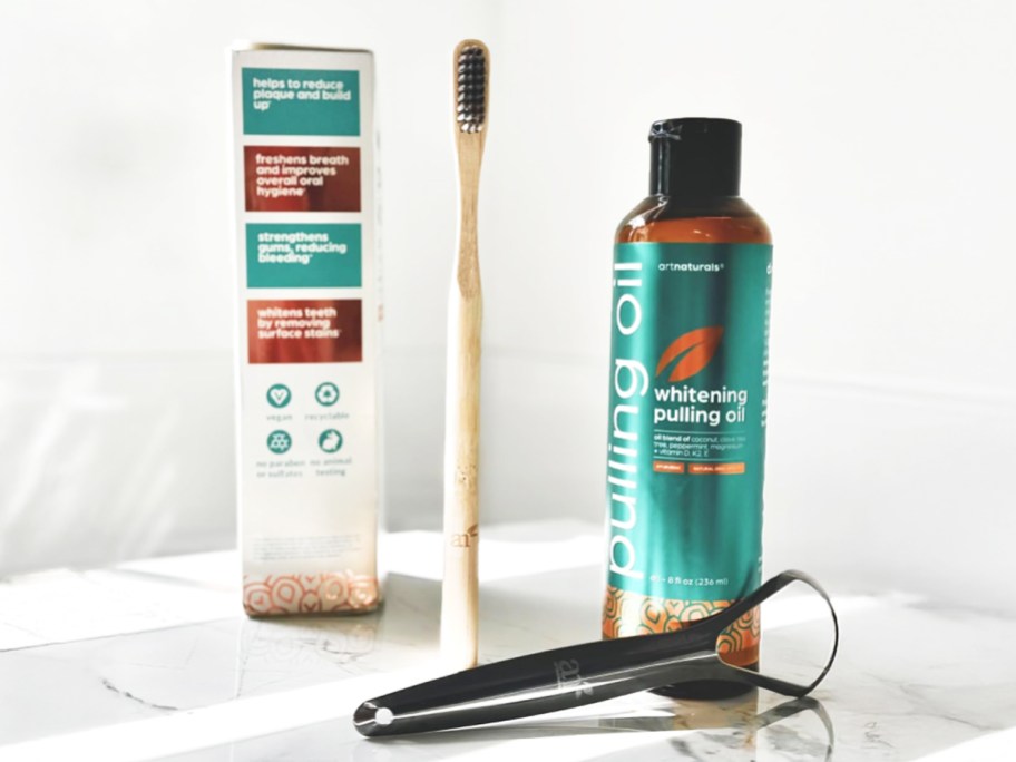 bottle of pulling oil, bamboo toothbrush, and tongue scraper 