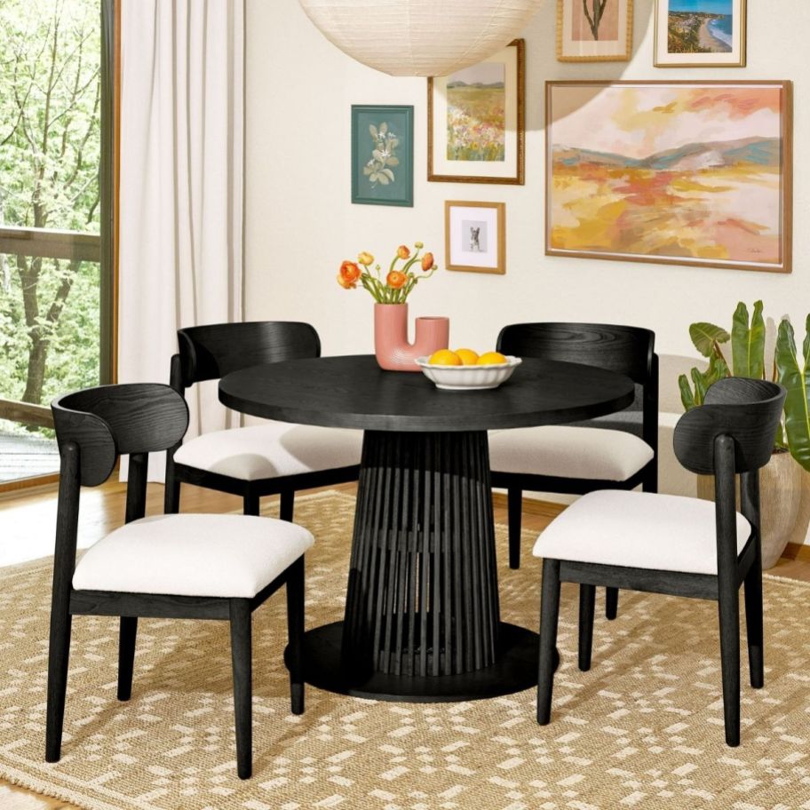 a black round dining table shown with 4 matching chairs