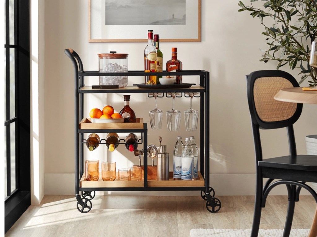 Black and wood bar cart with drinks and glasses in dining room
