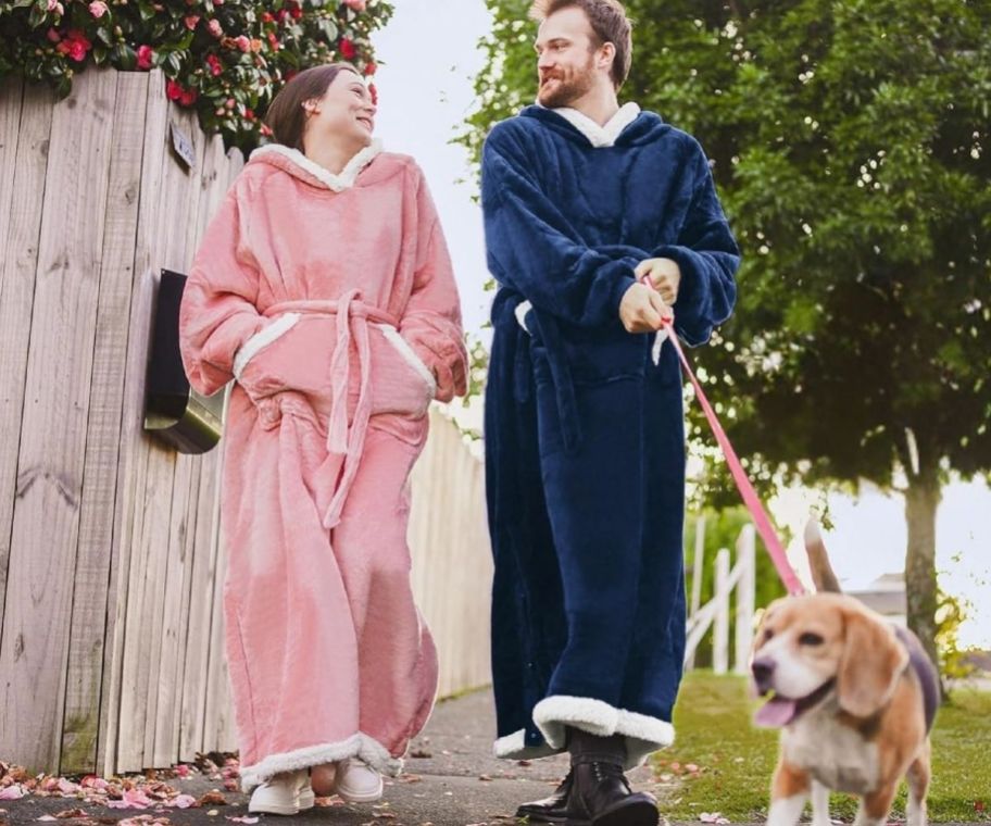 Couple wearing hoodie blanket while walking their dog outside