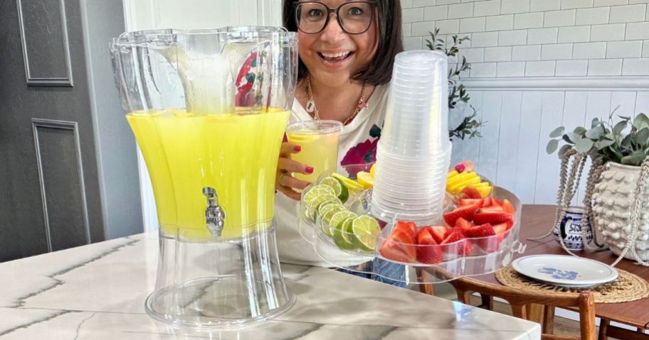 woman holding a party top lid filled with fresh fruit garnishes and plastic cups from a Buddeez Beverage dispenser