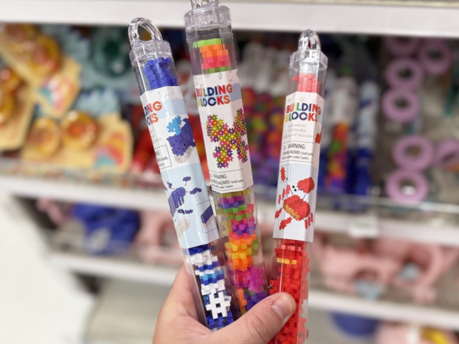 hand holding 3 tubes full of colorful building blocks