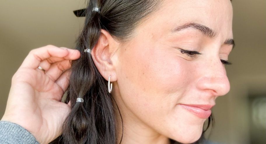 Woman showing her little hoop earring with her head tilted to the side
