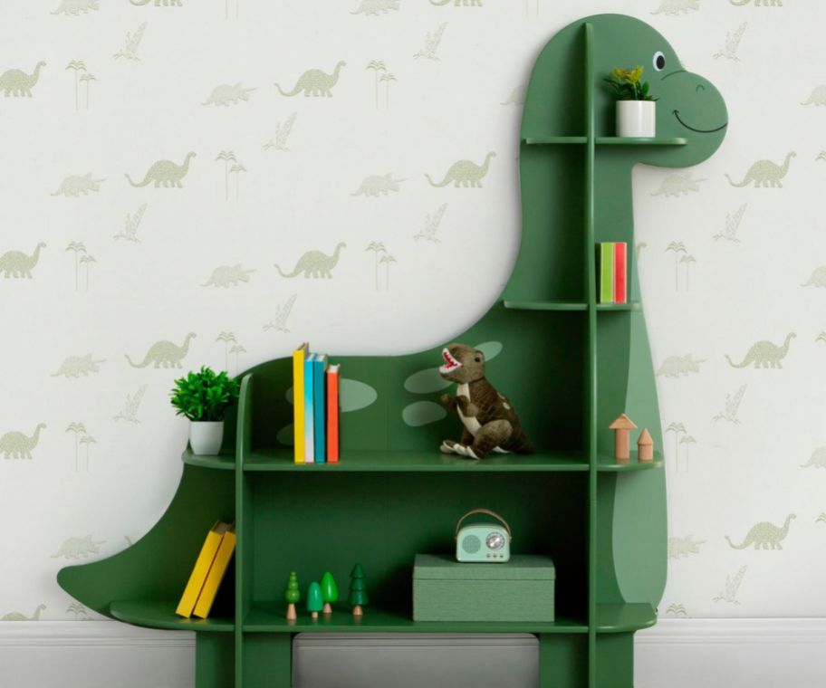A green dinosaur bookshelf with books on it 