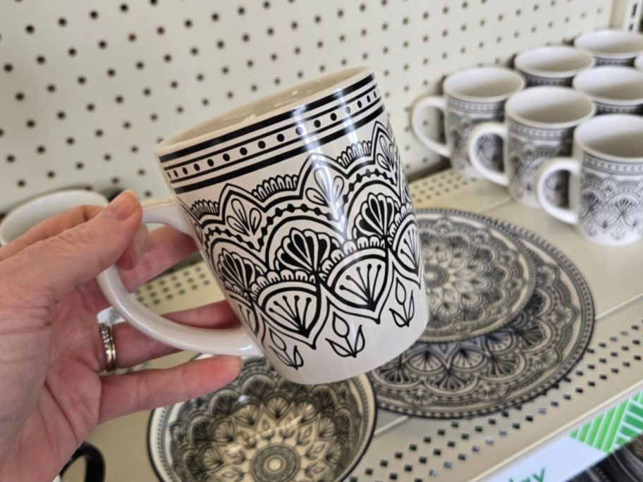 A person holding a black and white geometric patterned mug