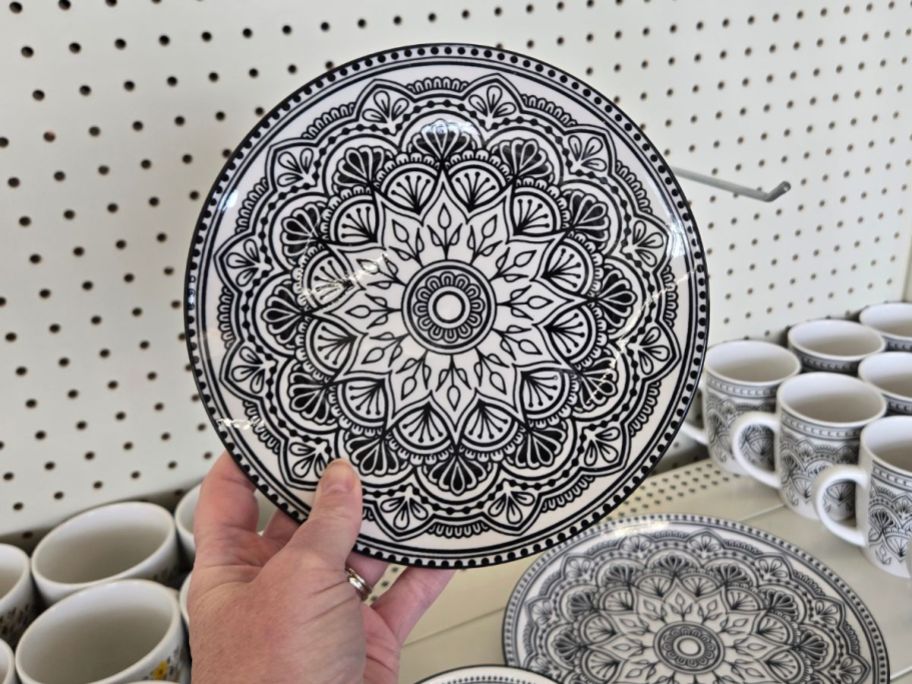 A person holding a black and white geometric patterned plate