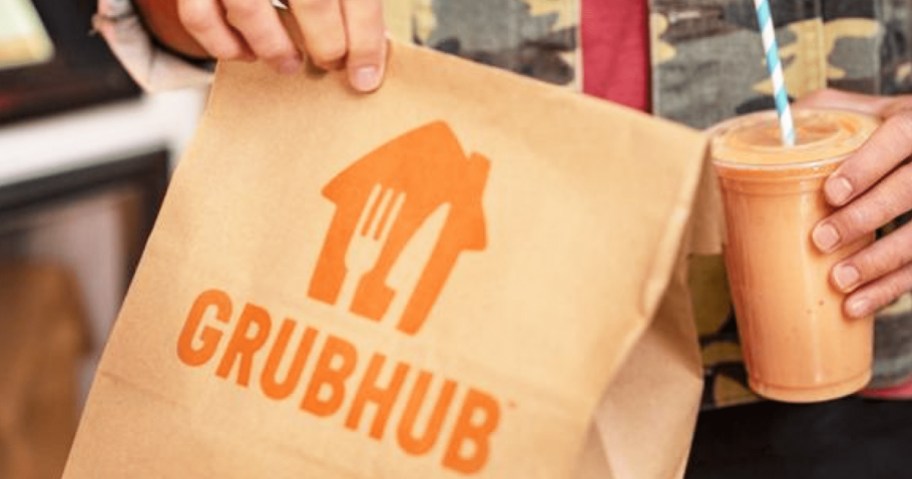 person holding a brown paper grubhub bag and an iced coffee
