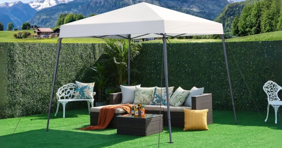 a white pop up canopy tent in a backyard with patio furniture under it
