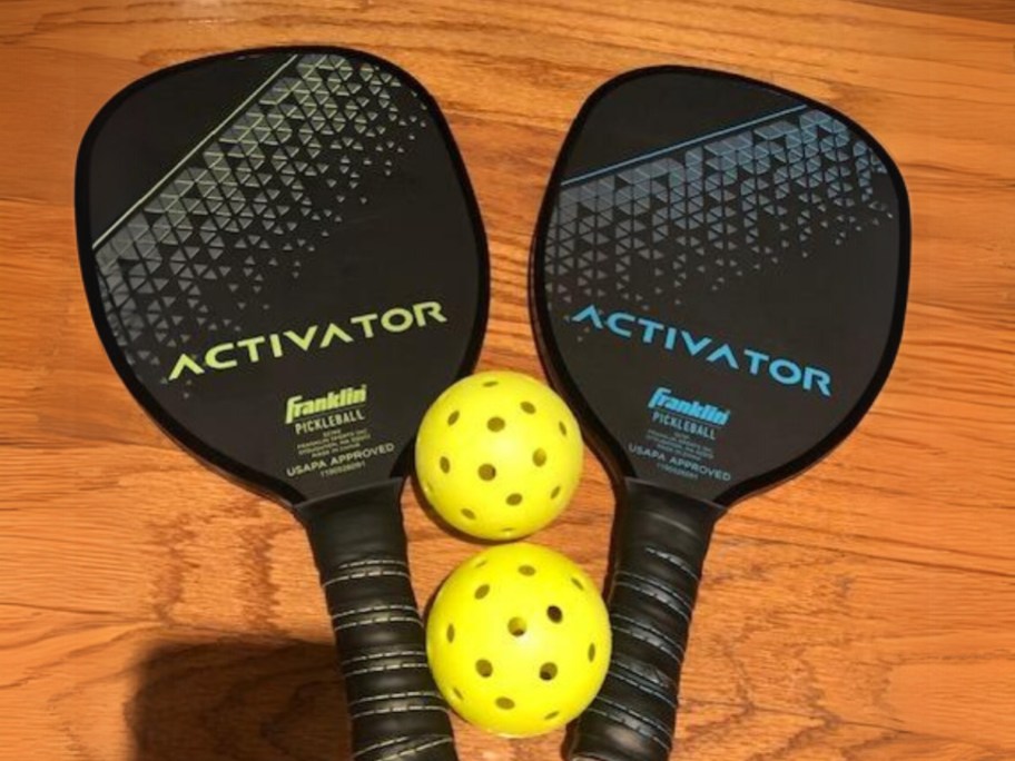 2 pickleball paddles and 2 balls on wood table