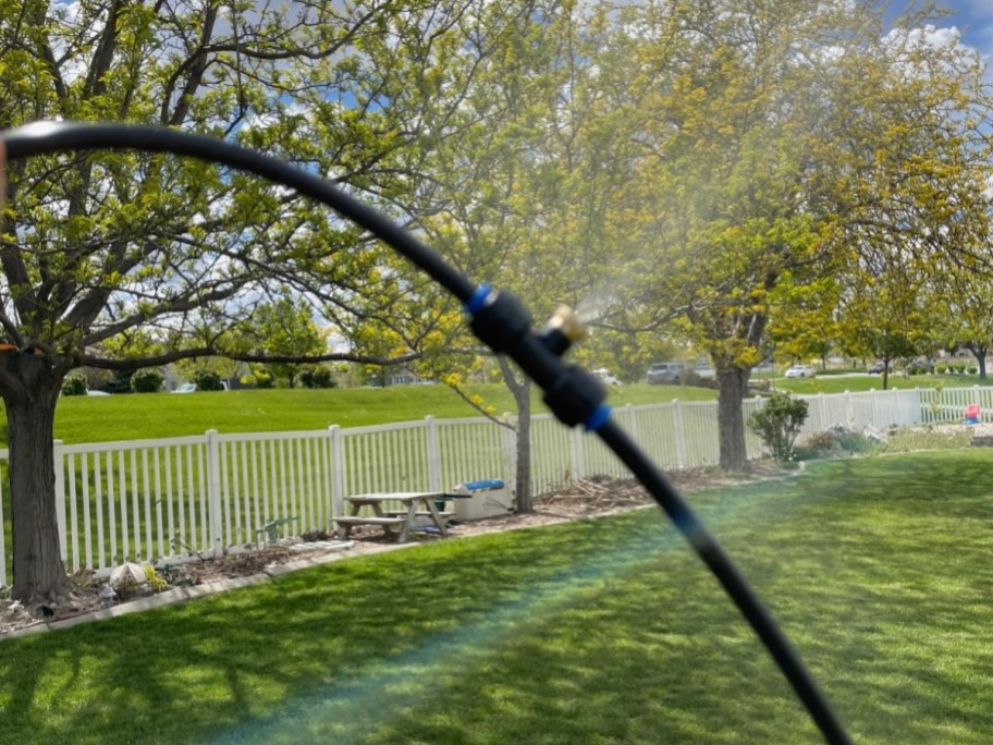 a hose misting water out in a backyard