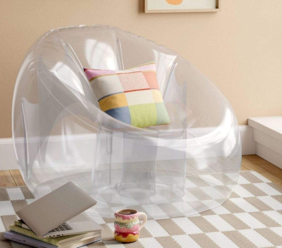 a clear vinyl inflatable chair shown with a throw pillow