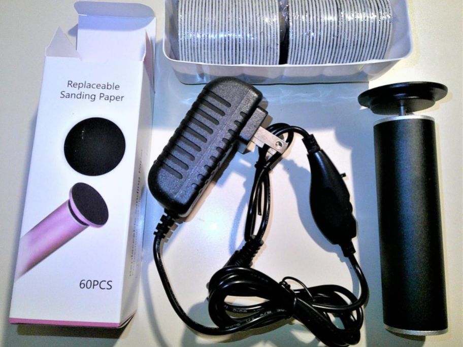 A box containing a black electric foot file, plug, and replacement pads