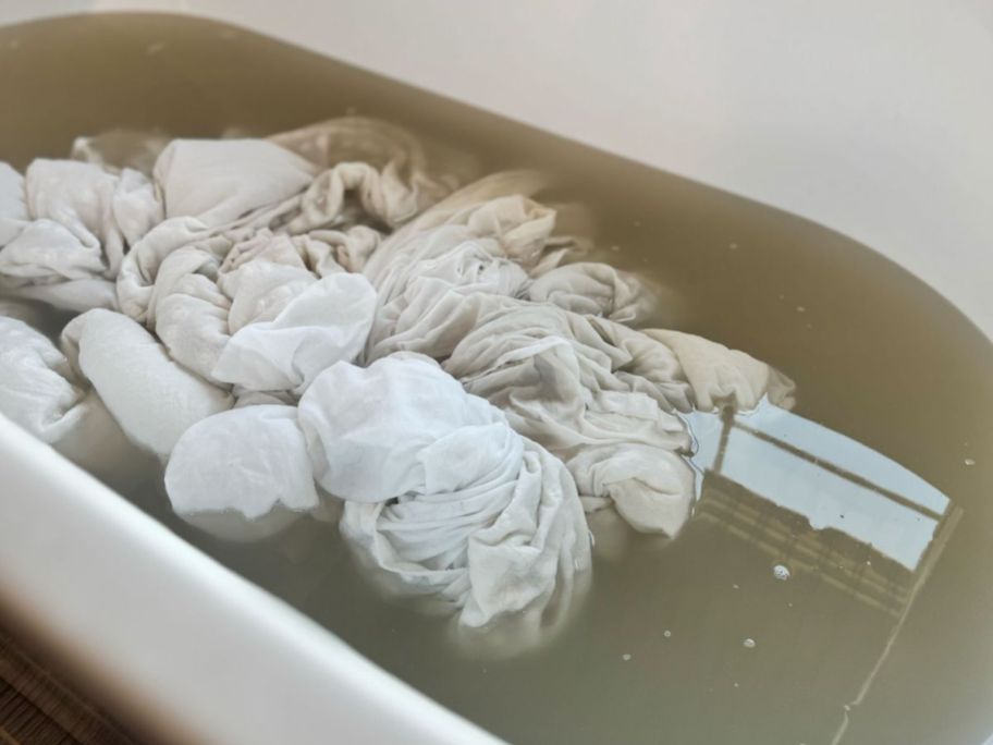 duvet inside of a tub with murky water as it is being laundry stripped