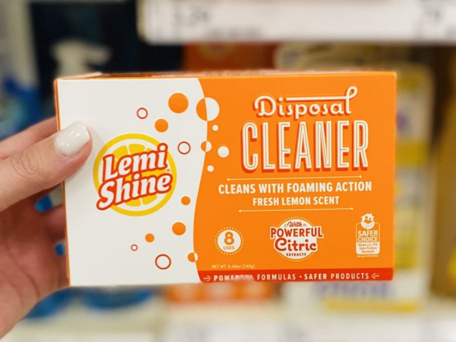 Hand holding a box of Lemi Shine disposal cleaner