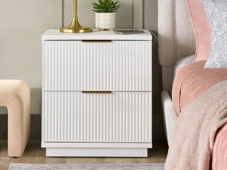 a white 2-drawer nightstand next to a bed