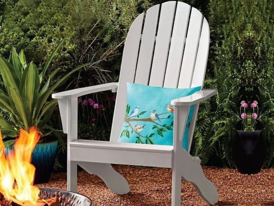 A white mainstays adirondack chair next to a fire pit