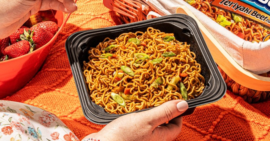 woman holding a black bowl of Maruchan Yakisoba noodles with sliced green onions
