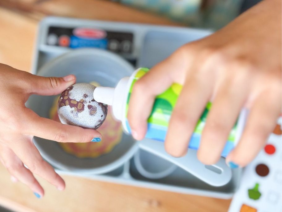hand squirting water onto a piece of food from the Melissa & Doug Water WOW Saute & Serve Play Set