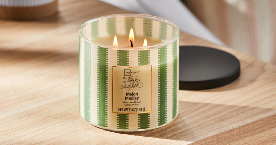 Green and white striped melon medley, three wick candle on wooden table