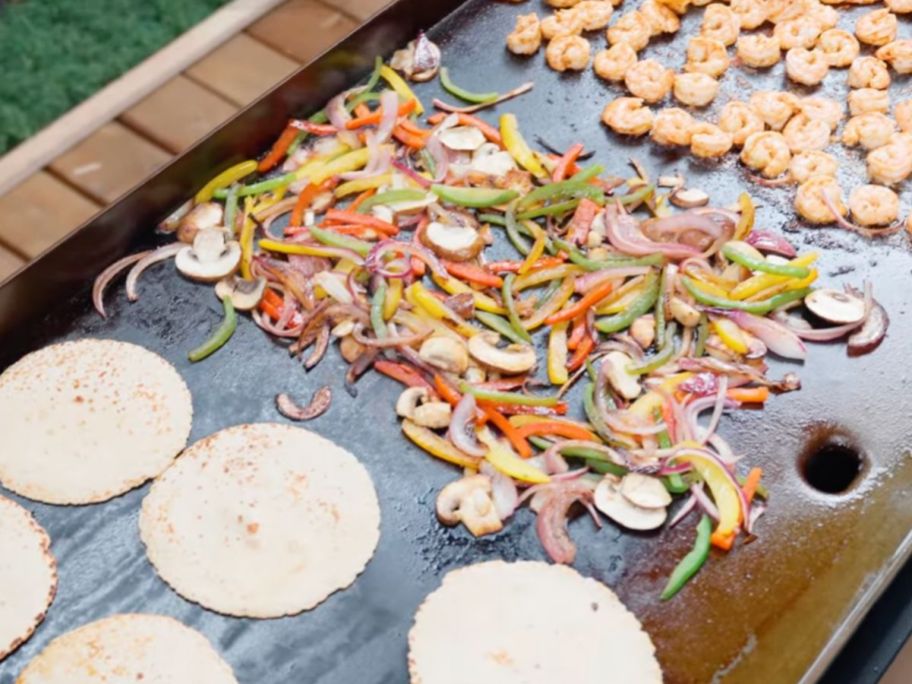 A Member's Mark Griddle with tortillas, fajita veggies ad shrimp on the flat top.