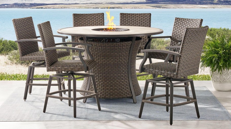 6 brown patio chairs around tall round fire pit