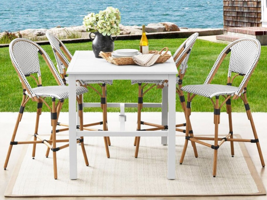 white patio table with 4 white and black chairs around it